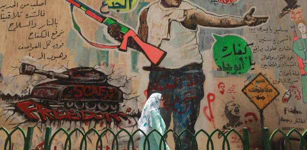 Mulher passa por mural na cidade do Cairo, no Egito