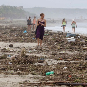 Turista caminha por praia coberta de escombros após a passagem do furacão em Puerto Escondido