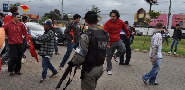 Torcedor pula ao ver policial com arma de balas de borracha na chegada de Forlán 