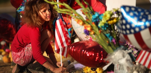 Criança coloca uma bandeira dos Estados Unidos em memorial improvisado para as vítimas do tiroteio em cinema em Aurora, Colorado (EUA) (22/7/12)