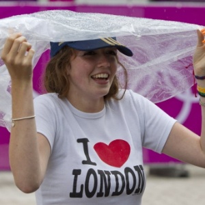 Mulher com camiseta "Eu amo Londres" se cobre para fugir da chuva na capital britânica