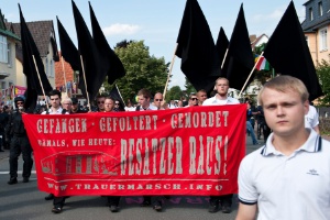 Neonazistas marcham em uma comunidade judaica, carregando faixas e bandeiras na Alemanha