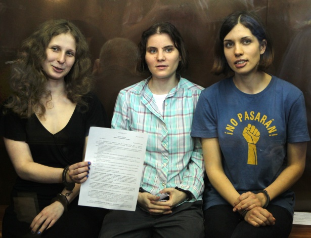Nadezhda Tolokonnikova (à esq.), Maria Alyokhina e Yekaterina Samutsevich (à dir.), do grupo punk Pussy Riot, exibem o veredito após serem senteciadas a dois anos de prisão, no tribunal, em Moscou (17/8/12)