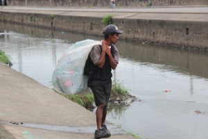Para sobreviver, Jéferson de Souza  Lopes cata garrafas pet às margens do rio Faria-Timbó, na favela de Manguinhos, no Rio de Janeiro