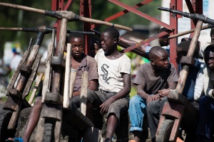 Jovens congoleses sentam em  bicicletas de madeira em Sake, na República Democrática do Congo