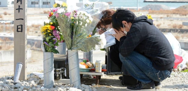 Casal faz orações em memorial para as vítimas do terremoto seguido de tsunami que devastou o Japão em 2011 e matou cerca de 19 mil pessoas, em área devastada pela tragédia em Natori,