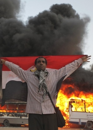 Manifestante egípcio exibe bandeira do país durante protestos em que ônibus da Irmandade Muçulmana, que governa o país, foram incendiados, no bairro de Moqattam, no Cairo