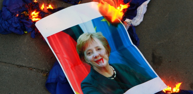 Foto desfigurada da chanceler alemã, Angela Merkel, é posta em chamas durante protesto de bancários no Chipre