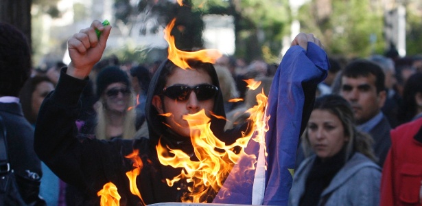 Manifestante coloca fogo em bandeira da União Europeia durante protesto em Nicosia, capital do Chipre