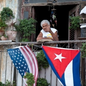 Cubano acena de varanda decorada com bandeiras dos EUA e de Cuba, em Havana, em foto de janeiro de 2015