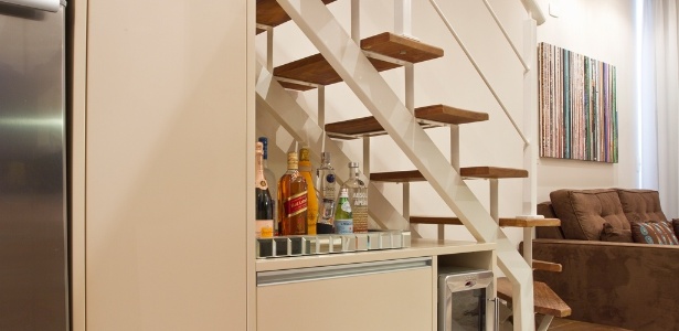O vão da escada foi ocupado pelo móvel em madeira laqueada, com design assinado por Camila Klein