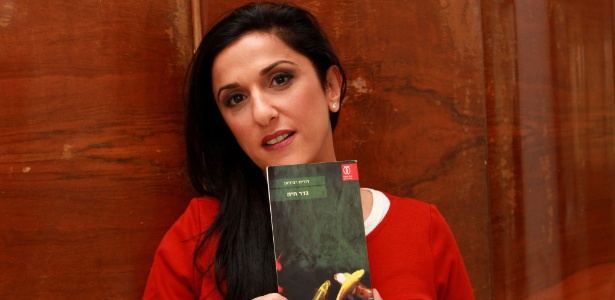 31.dez.2015 - A escritora israelense Dorit Rabinyan posa com seu romance "Uma Barreira Viva" em sua casa, em Tel Aviv