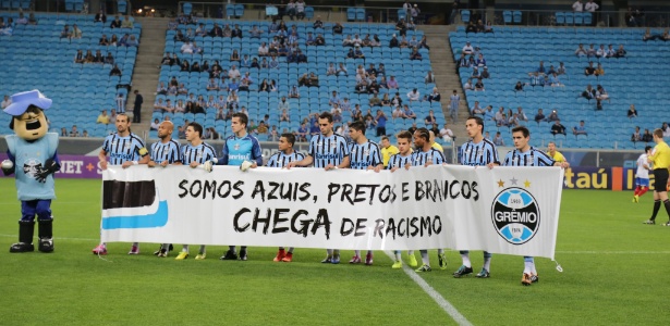 Jogadores do Grêmio entram em campo para o jogo com o Bahia com faixa contra o racismo