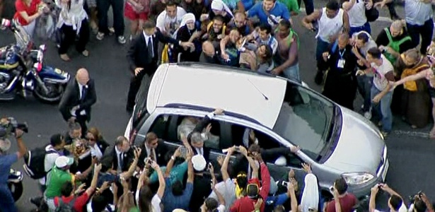 Fiéis se aglomeram ao redor do carro que conduz o papa Francisco pelas ruas do centro do Rio