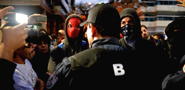 Tasso Marcelo/Afp Manifestantes mascarados ouvem recomendações de PM durante protesto nos arredores da residência do governador do Rio no dia 25 de julho