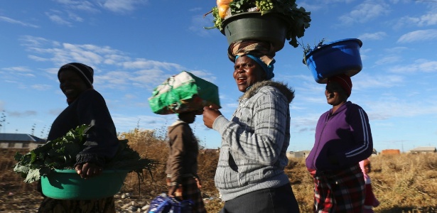 Mulheres carregam alimentos na cabeça, em Chitungwiza, ao sul de Harare, no Zimbabue