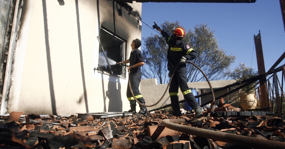  - 5ago2013---bombeiros-trabalham-em-uma-casa-parcialmente-queimada-na-aldeia-de-avra-perto-da-cidade-de-maratona-na-grecia-1375728358418_956x500