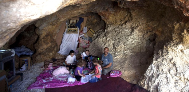 O palestino Khaled Zir al-Husseini e seus filhos na caverna onde moram desde que a casa da família, em Jerusalém Oriental, foi demolida por forças israelenses