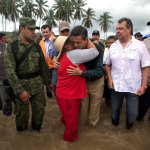 Com água nas canelas, o presidente do México, Enrique Piña Nieto, abraça moradora durante encontro com comunidades afetadas pelas tempestades tropicais no Estado de Guerrero, em setembro