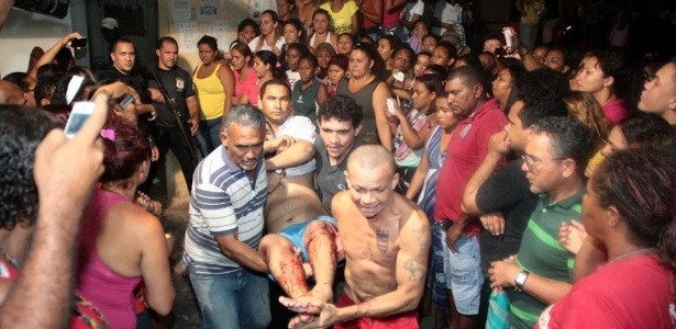 Familiares e amigos carregam detento ferido durante uma briga entre integrantes de facções criminosas rivais que estão presos no Complexo Penitenciário de Pedrinhas