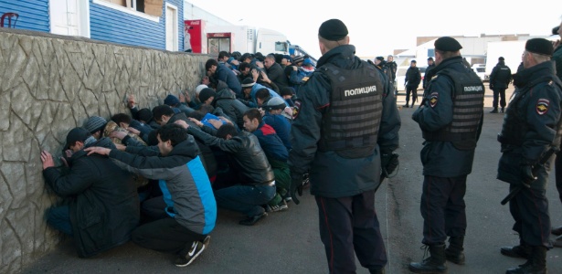 Policiais russos detêm imigrantes durante operação realizada em um mercado de vegetais no distrito moscovita de Biryulyovo. Mais de mil imigrantes foram detidos no local, invadido no domingo