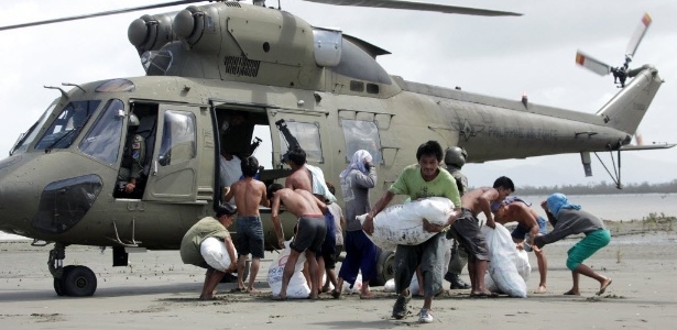 Sobreviventes do tufão Haiyan na vila de Capiz carregam sacos com mantimentos básicos