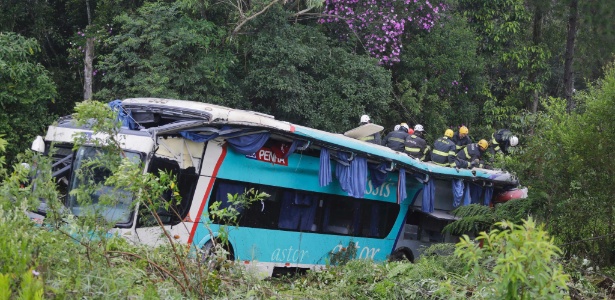 Bombeiros trabalham para retirar vítimas das ferragens do ônibus que caiu dentro de um barranco