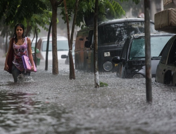 Jovem anda em trecho tomado por alagamento na rua Frederico Steidel, em Santa Cecília (zona oeste de São Paulo), durante o temporal que atingiu a capital na tarde desta sexta-feira (24)