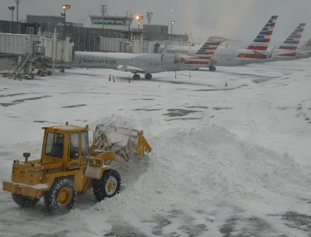 Escavadeira retira neve do aeroporto de La Guardia, em Nova York, nesta quinta-feira (13). Uma forte tempestade de inverno levou neve e granizo à região leste dos EUA, provocando o cancelamento de voos