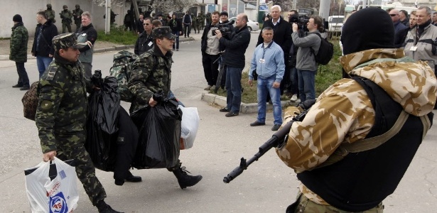 Soldados ucranianos carregam seus pertences enquanto deixam a base da Marinha em Sevastopol, na Crimeia, nesta quarta-feira (19), após soldados encapuzados pró-Russia assumirem o controle do posto