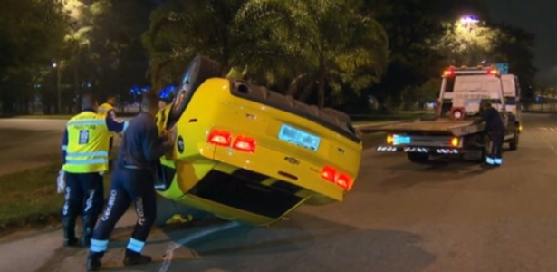Agentes da CET-Rio tentam desvirar o Camaro amarelo que capotou na Barra da Tijuca, zona oeste do Rio