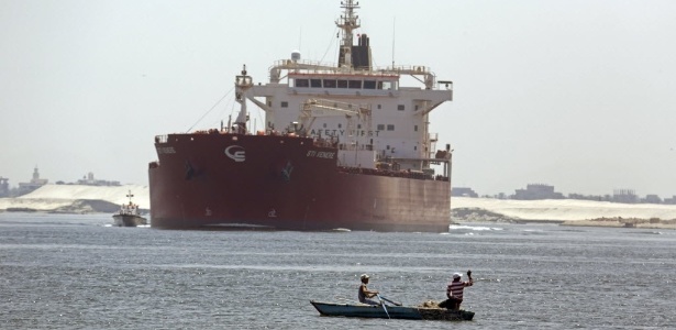 Egípcios pescam em frente de um navio maltês que cruza o canal de Suez, em Ismailia