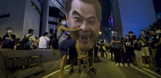 Ativista atinge recorte com rosto do chefe do executivo de Hong Kong, Leung Chun-ying