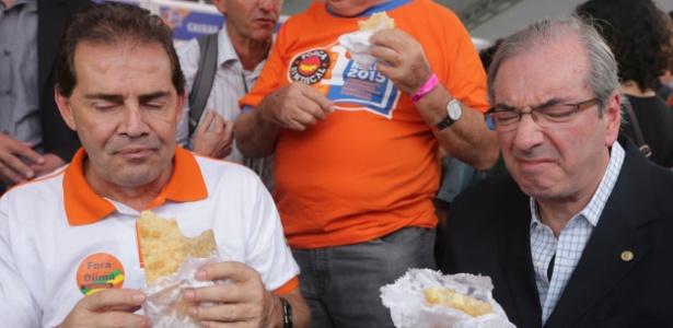 Os deputados Paulinho da Força (SD-SP) e Eduardo Cunha (PMDB-RJ) comem pastel durante festa da Força Sindical