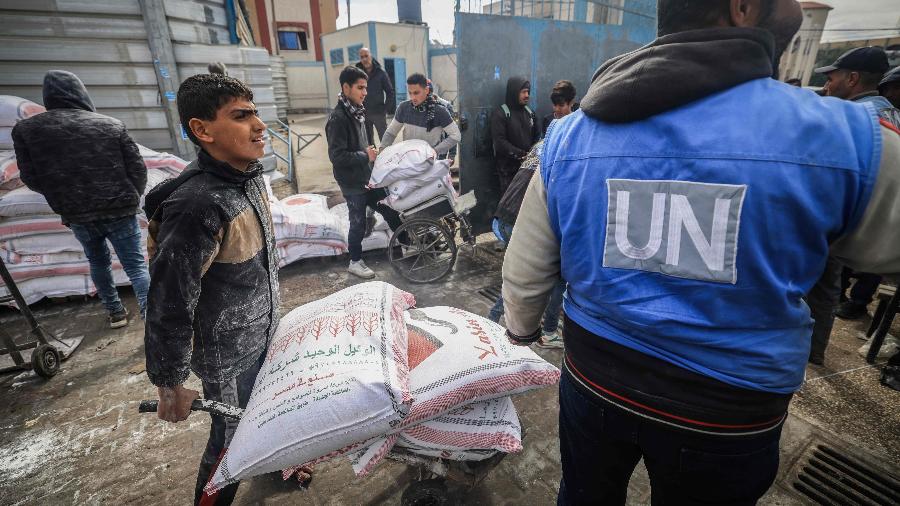 Refugiados palestinos recebem sacos com alimentos da UNRWA em Rafah, no sul da Faixa de Gaza