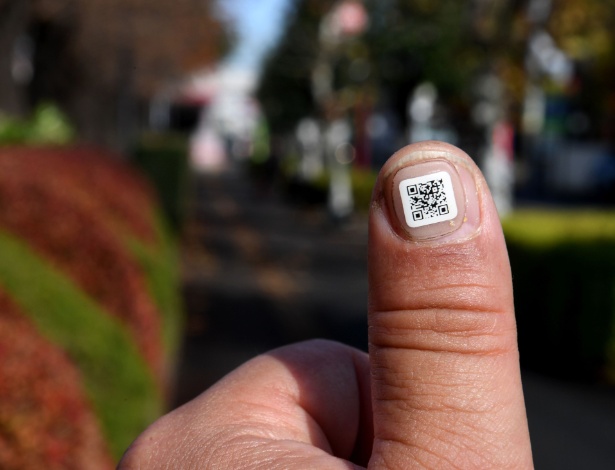 Funcionário da prefeitura mostra código QR na unha próximo à cidade de Iruma, Saitama (Japão)