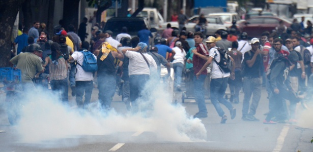 Federico Parra/AFP Manifestantes são dispersados por bombas de gás lacrimogêneo em Caracas, na Venezuela