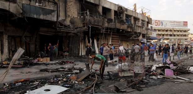 Populares retornam ao local onde um carro-bomba foi detonado em Bagdá, no Iraque, em 21 de julho. O país foi alvo de quatro ataques terroristas com carros-bomba, todos atribuídos ao grupo terrorista Estado Islâmico (EI)