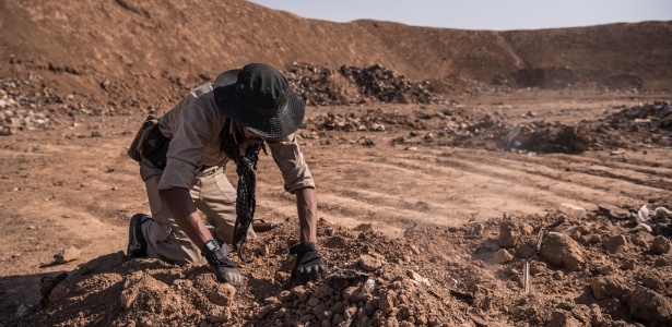 Soldado procura por corpos em uma vala comum localizada em um aterro em Hamam al-Alil, Iraque