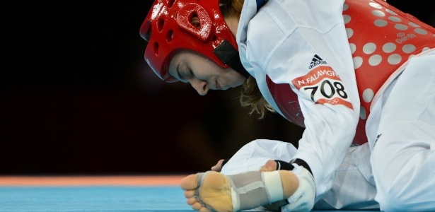 Natália Falavigna segura a perna durante o primeiro round da derrota para coreana na estreia do taekwondo