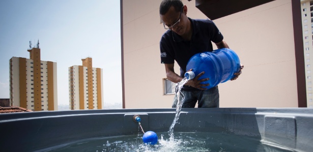 Funcionário do restaurante Mocotó, em São Paulo, enche caixa d'água com galões de água mineral