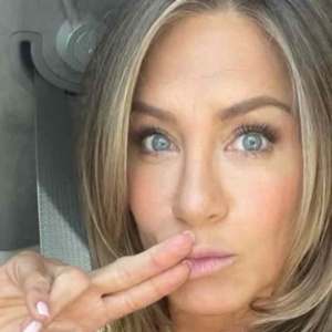 Jennifer Aniston com dedo na boca em banco do carro